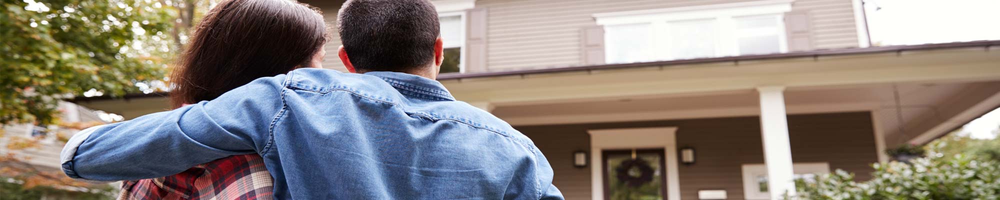 Young couple standing outside looking at their newly purchased home.